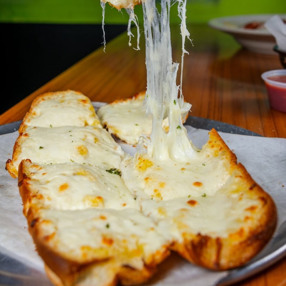 Cheesy garlic bread with melted mozzarella stretching upwards, served on a tray at Mama's Pizza & Grill.